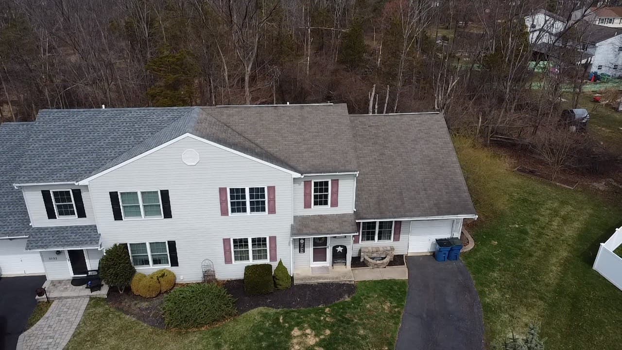 Aerial view of a completed asphalt shingle roof replacement on a white two-story colonial home in southeastern Pennsylvania