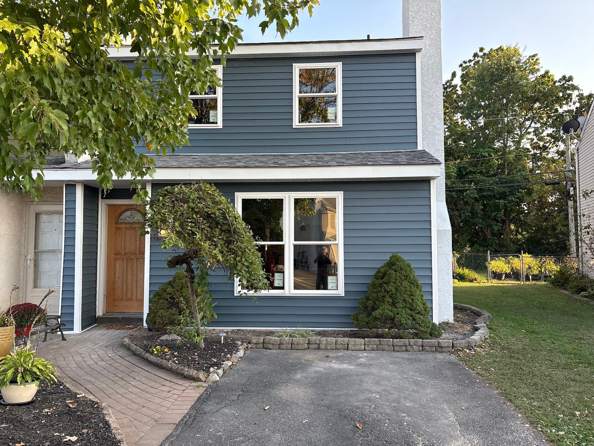Two-story home after a complete siding replacement in slate blue lap siding with white trim and a new picture window